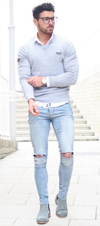 Серый свитер с v-образным вырезом отлично сочетается с голубыми рваными зауженными джинсами. Сделать образ изысканнее помогут серые ботинки челси.