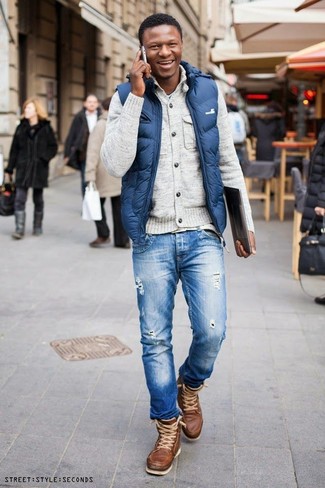 Синяя куртка без рукавов и синие рваные джинсы — must have вещи в стильном мужском гардеробе. Создать модный контраст с остальными вещами из этого образа помогут коричневые рабочие ботинки.