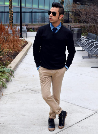 Приверженцам стиля casual должно понравиться сочетание черного свитера с v-образным вырезом и бежевых брюк чинос. И почему бы не разбавить образ с помощью черных кожаных высоких кед?