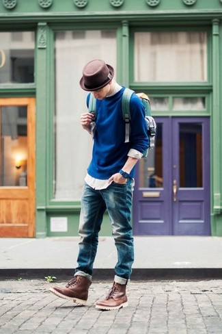 Темно-синий свитер с круглым вырезом и синие джинсы — выгодные инвестиции в твой гардероб. Очень выигрышно здесь будут смотреться коричневые кожаные ботинки.