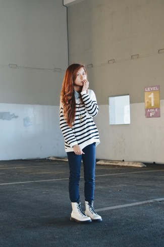 Бело-темно-синий свободный свитер в горизонтальную полоску и темно-синие джинсы скинни — стильный выбор девушек, которые постоянно в движении. Выбирая обувь, можно немного побаловаться и завершить образ белыми кожаными ботинками.