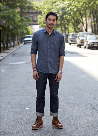Приверженцам стиля casual должно понравиться сочетание синей рубашки с длинным рукавом из шамбре и темно-синих джинсов. Этот образ идеально дополнят коричневые рабочие ботинки.
