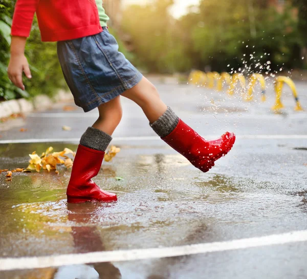 Ребенка, ношение красного дождя сапоги, прыгнув в луже — стоковое фото