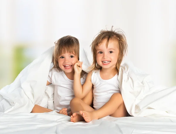 Сестра-близнец счастливый маленькая девочка в кровати под одеяло с — стоковое фото