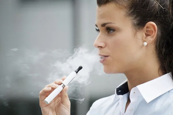 Молодая женщина, Курение электронных сигарет открытый Офисное здание — стоковое фото