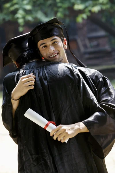 Выпускники колледжа обниматься — стоковое фото