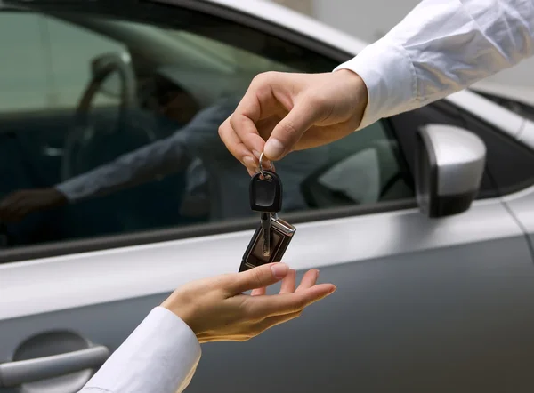 Женщина, получающая ключи от машины от человека — стоковое фото