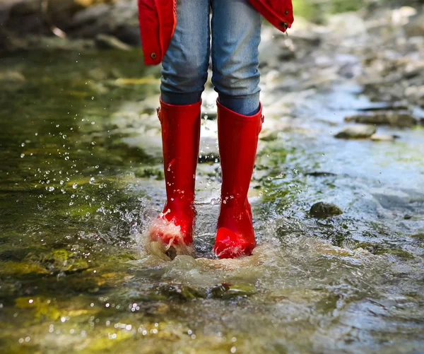 Ребенок, ношение красного дождя сапоги прыжки. Крупным планом — стоковое фото