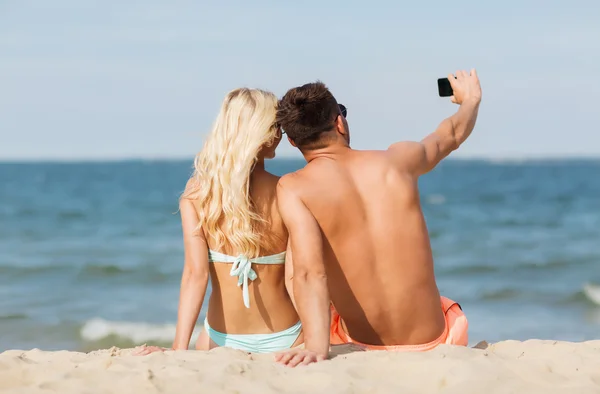 Счастливая пара в Купальники, сидя на пляже летом — стоковое фото