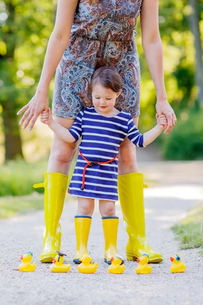 Мать и дитя очаровательны в желтые резиновые сапоги — стоковое фото