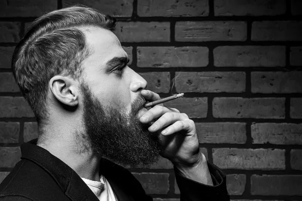 Молодой бородатый человек курить — стоковое фото