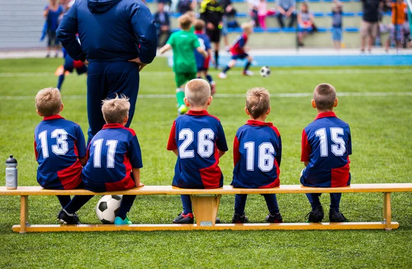Футбольный футбольный матч для детей. дети, смотрящие игру с тренером тренера и ждущие на скамье — стоковое фото
