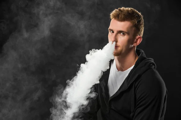 Молодой Бородатый Человек Выдыхая Дым Электронных Сигарет Окруженный Облака Пара — стоковое фото