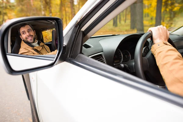 Улыбающийся водитель, отраженный в зеркале автомобиля — стоковое фото
