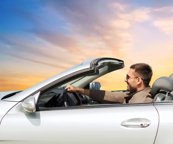 Happy man driving convertible car over sky — стоковое фото