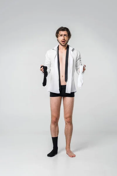 Shocked Young Man Shirt Underwear Holding Black White Socks Grey — стоковое фото