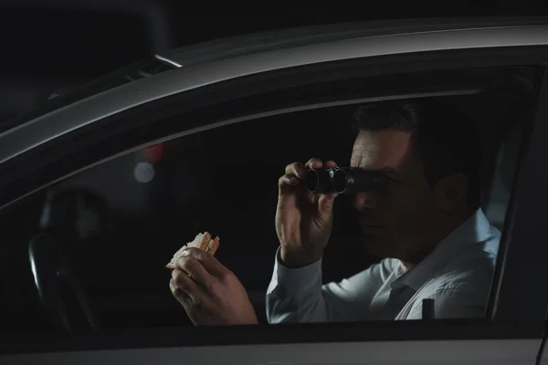 Мужчины Частный Детектив Делает Наблюдения Бинокли Ест Бутерброд Автомобиле — стоковое фото