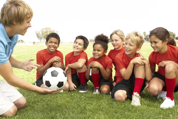 Маленькие мальчики и девочки в футболе подходят к тренеру — стоковое фото